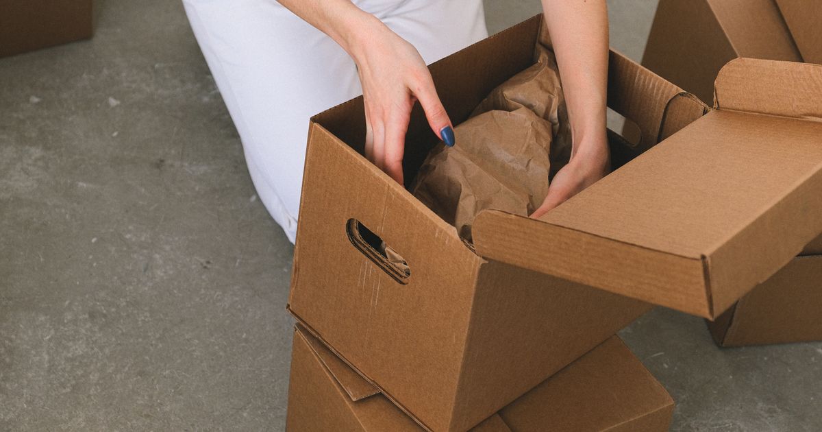 段ボール箱に荷物を梱包する手元(イメージ)