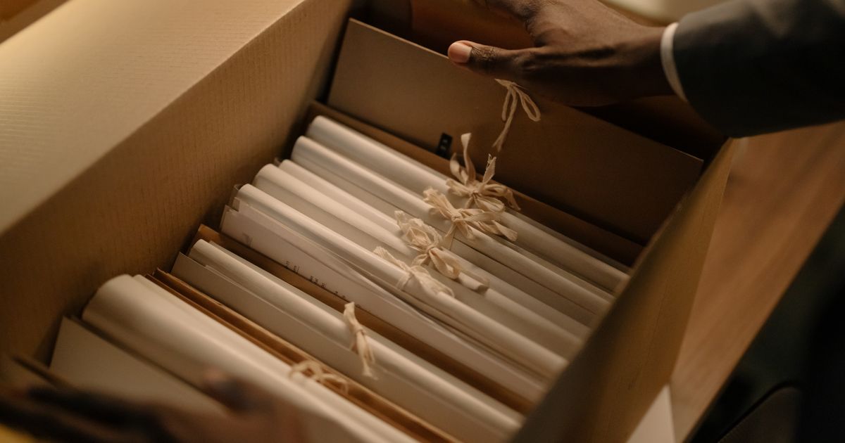 箱の中の書類をひもで束ねて整理する手元(イメージ)